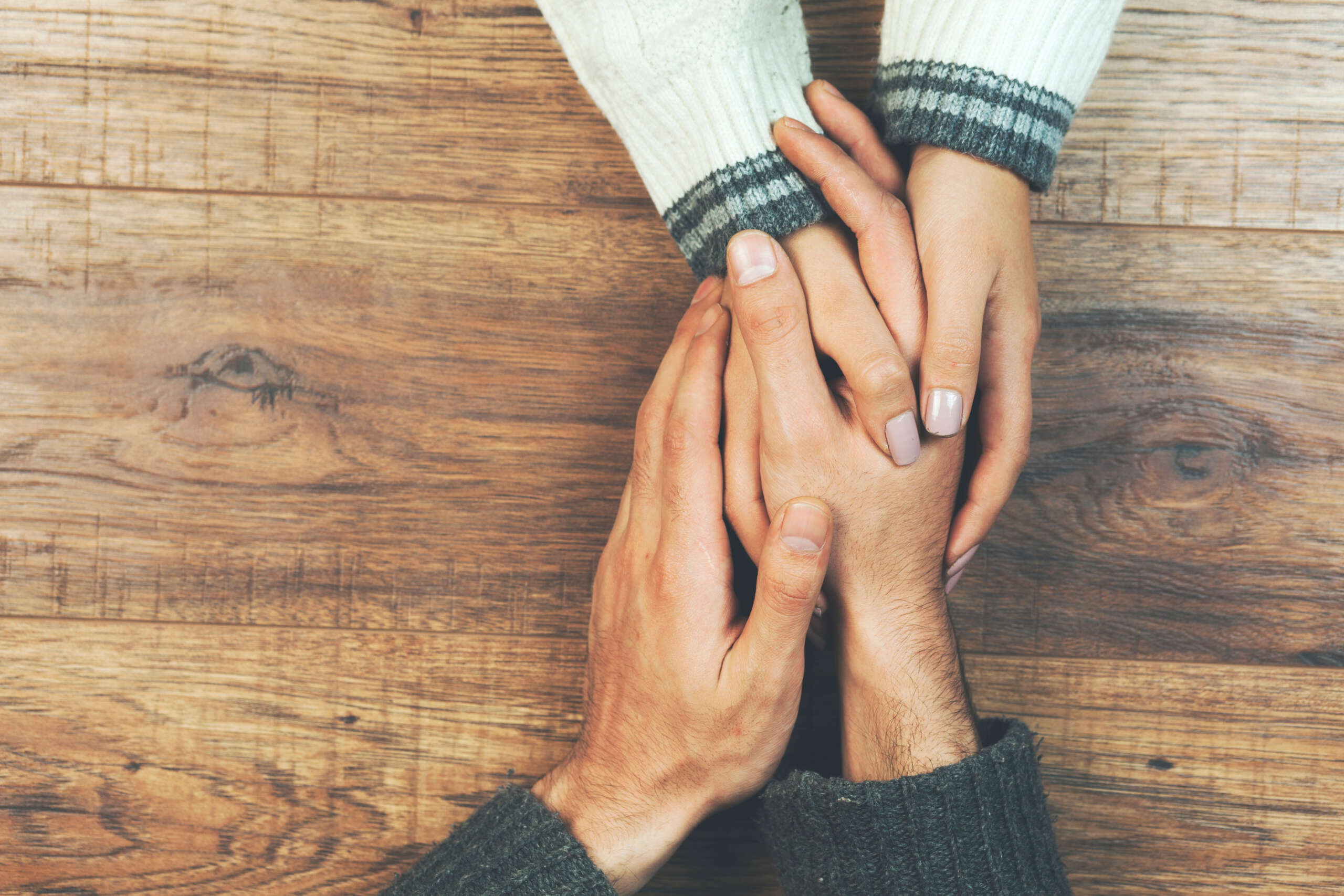 man and a woman holding hands at a wooden table